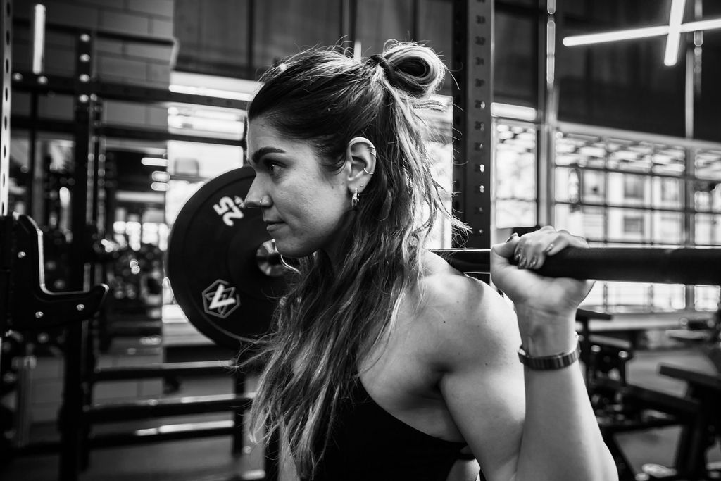 A member setting a barbell across her shoulders
